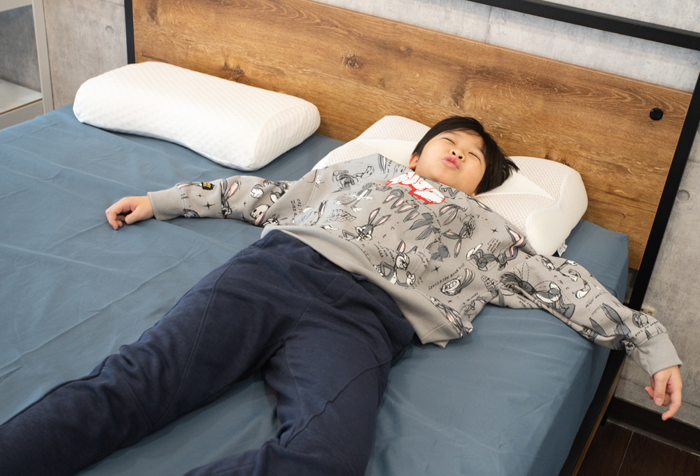 男性在藍色床包的床墊上仰躺試躺
