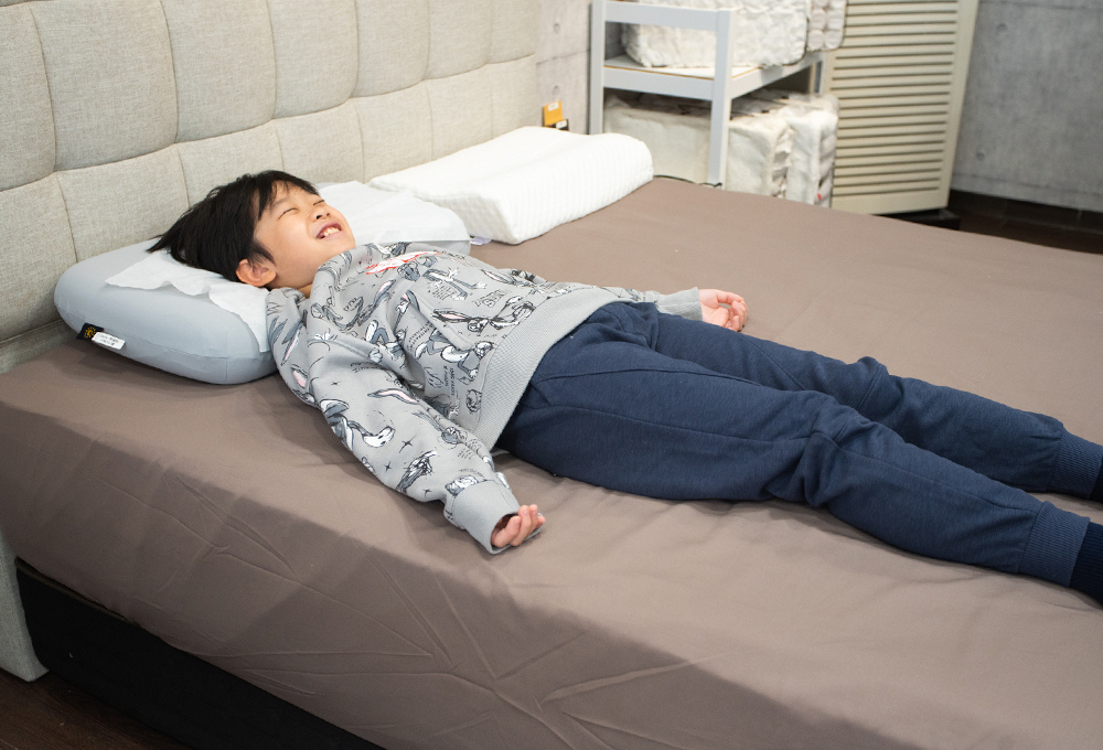 男性在褐色床包的床墊上仰躺,雙臂自然張開
